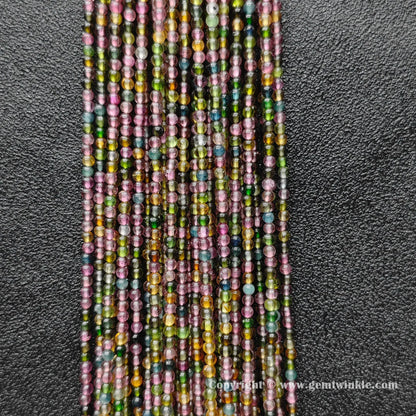 Finger holding small Grade B multi color tourmaline 2.5mm petite bead strands demonstrating scale