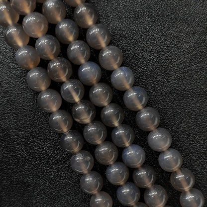 Close up view of three high gloss smoky grey agate smooth round beads strands showcasing misty translucent tones over a genuine natural base in image_bd33c9.jpg