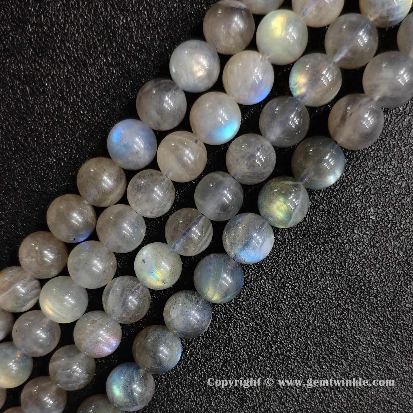 Row arrangement of smooth grey moonstone round bead strands with natural blue and white optical sheen