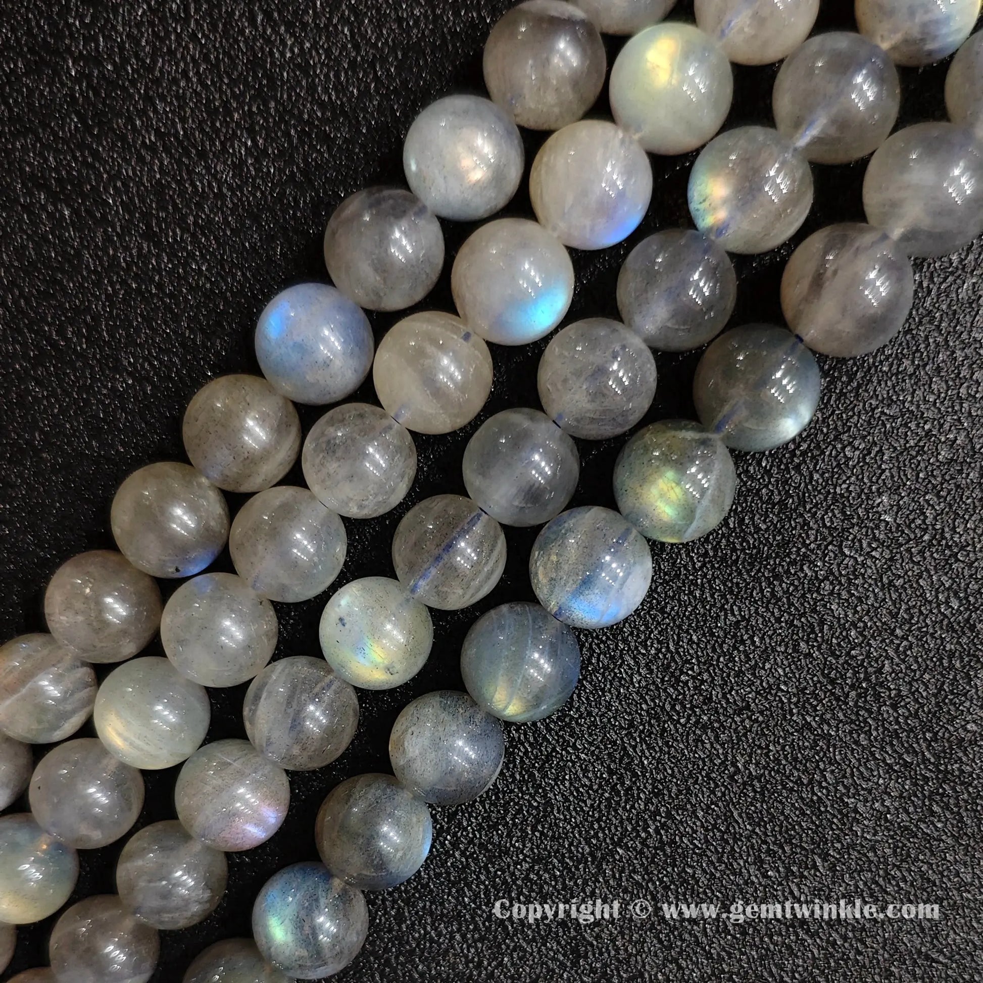 Row arrangement of smooth grey moonstone round bead strands with natural blue and white optical sheen