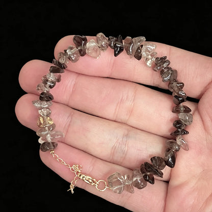 smoky quartz chip bracelet with gold tone extender chain held on open palm