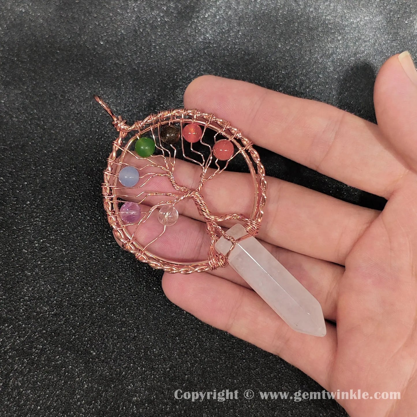Hand holding 8cm white crystal point pendant wrapped in antique copper metal alloy wire