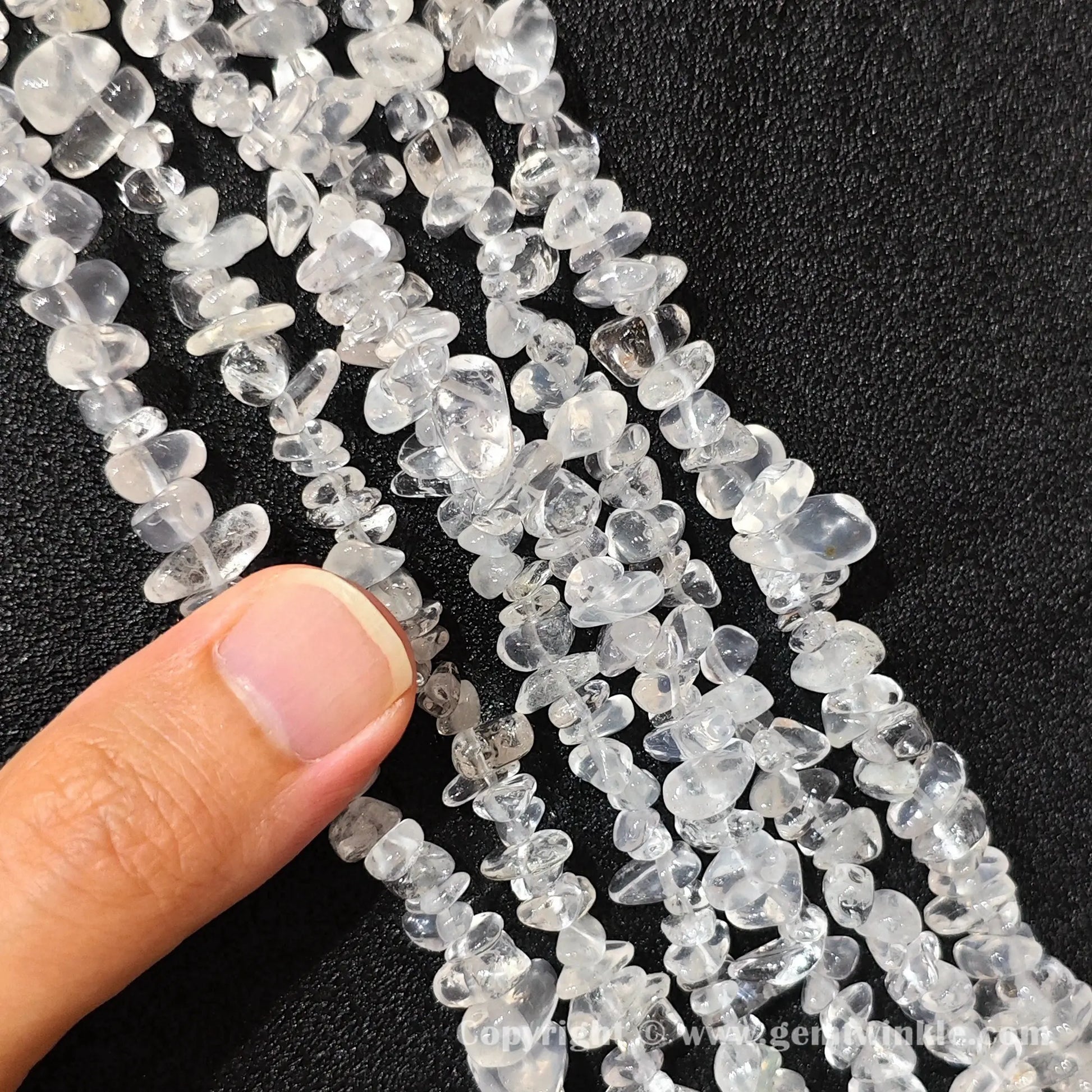 Hand holding 75cm continuous strand of milky snow quartz irregular chip beads