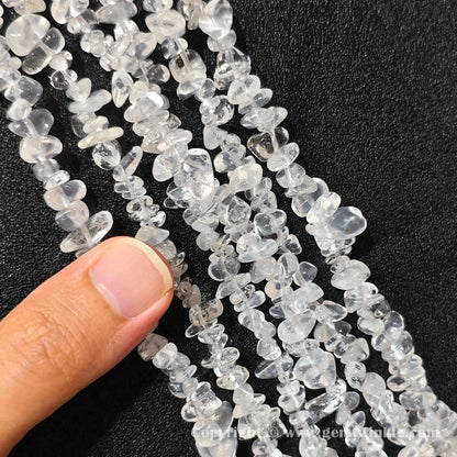 Hand holding 75cm continuous strand of milky snow quartz irregular chip beads