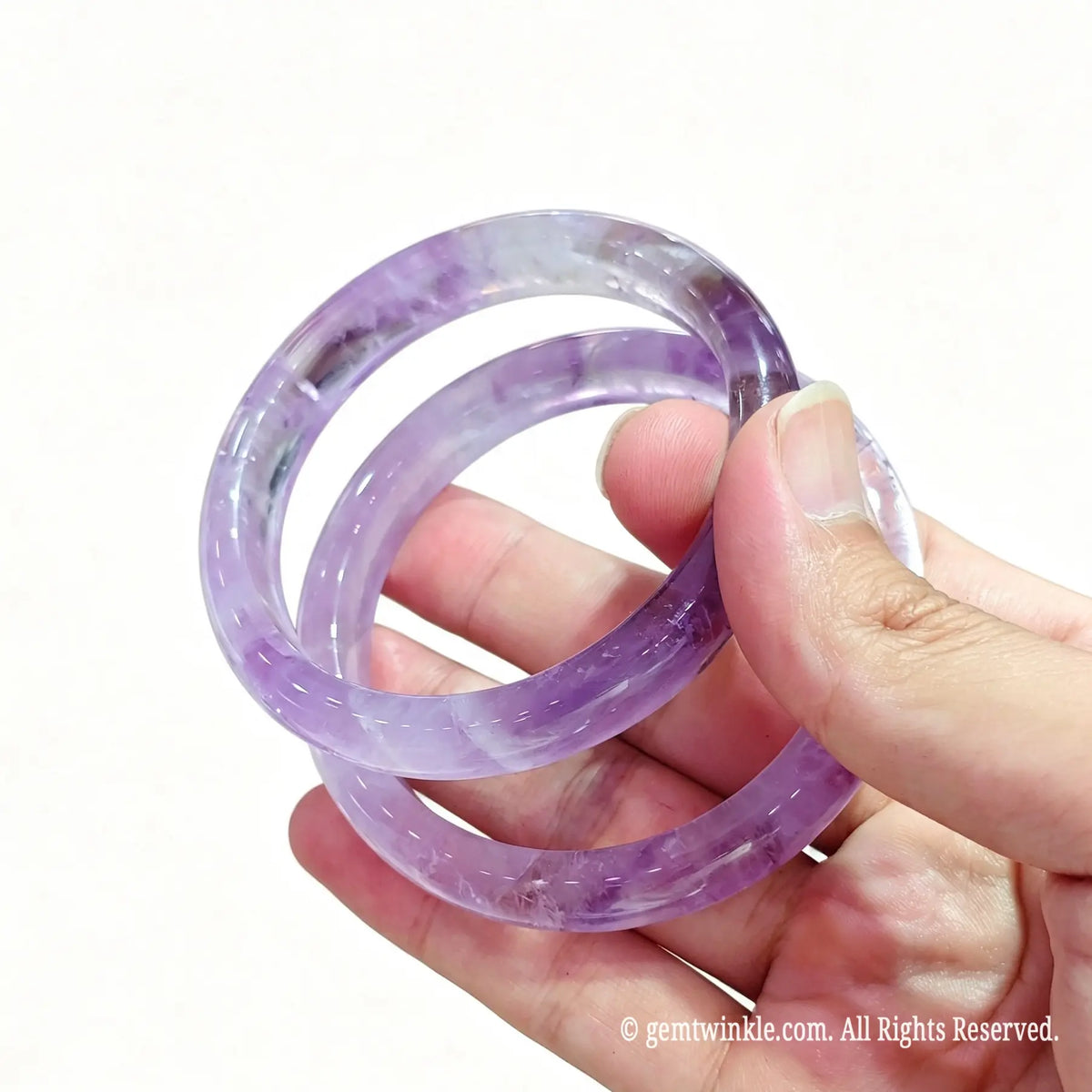 Two translucent light purple amethyst bangles displayed in hand for crystal shop owners