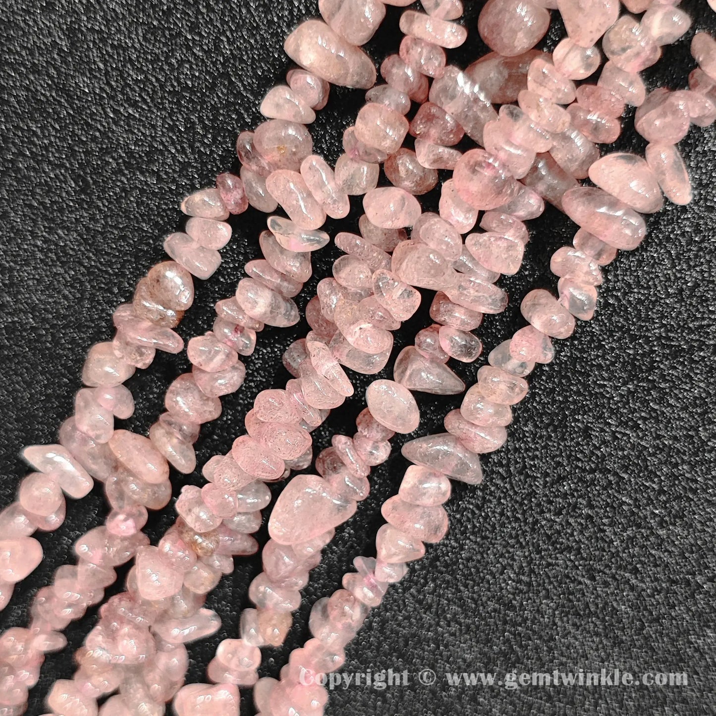 Close up view of tumbled speckled pink strawberry quartz freeform nugget chip beads