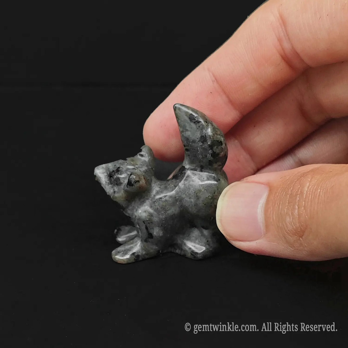 Handheld view of a 4cm rustic Spotted Grey Stone pocket puppy totem demonstrating miniature scale for boutique buyers