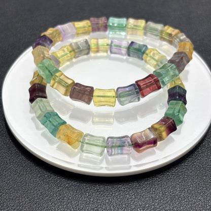 Two natural fluorite square bead bracelets displayed together on a white plate, highlighting the vibrant rainbow colors and bamboo texture.