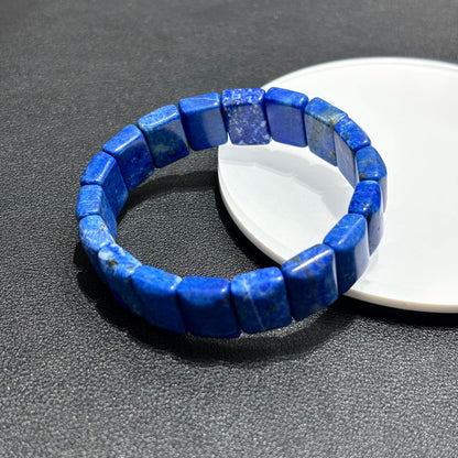  Two natural lapis lazuli square bead bracelets displayed together on a white plate, highlighting the rich blue color and golden inclusions.