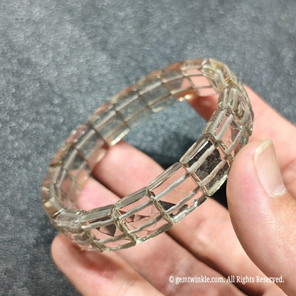 Perspective shot of stacked light smoky quartz plate bead strands resting across fingers under studio lighting