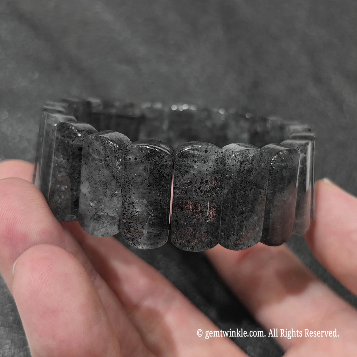Full view of a stacked unisex black strawberry quartz bracelet displayed under natural lighting