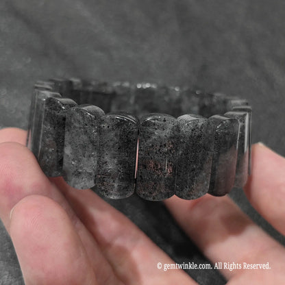 Full view of a stacked unisex black strawberry quartz bracelet displayed under natural lighting