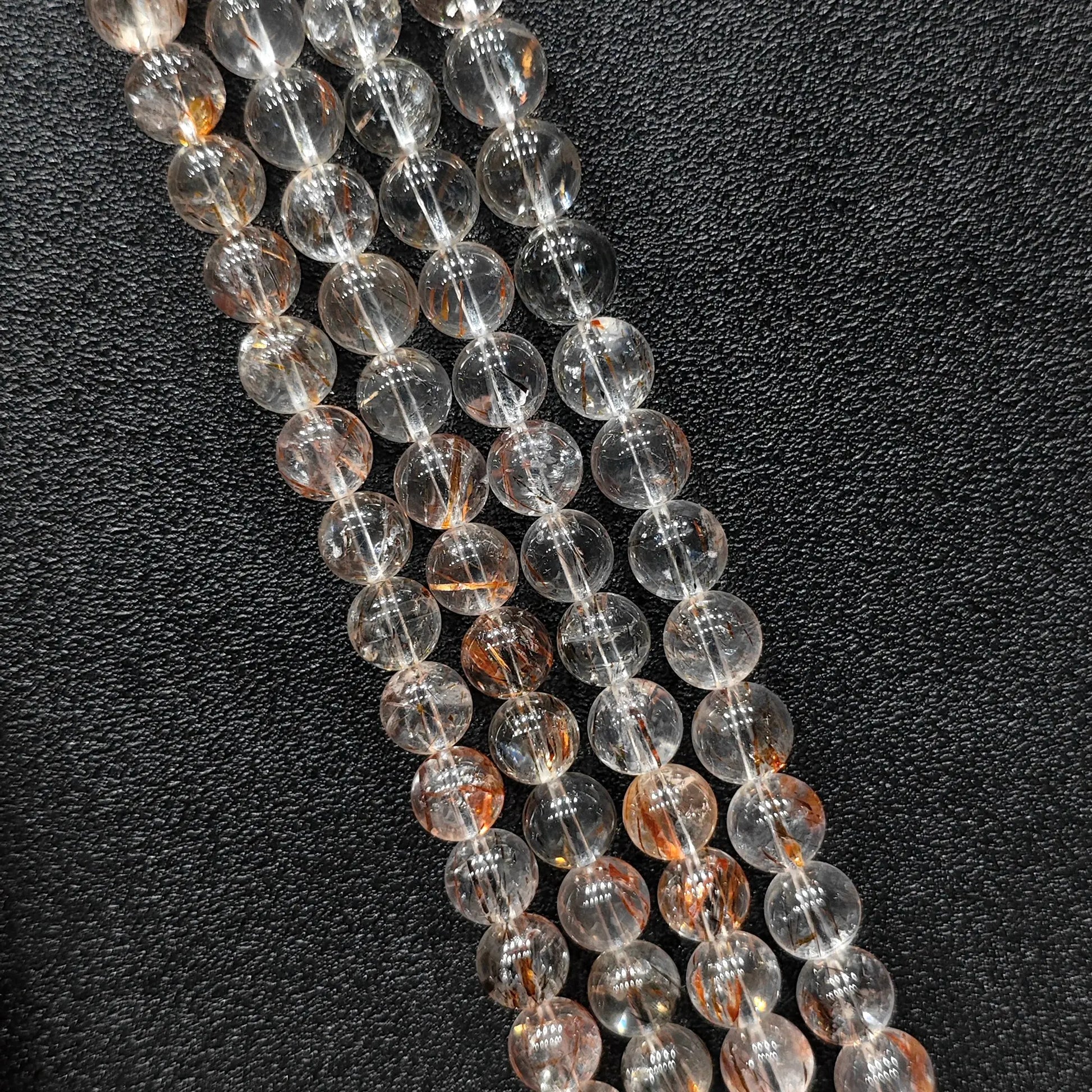 Close up view of statement gemstone beads showing natural copper rutilated quartz strands with clear matrix and reddish copper hair inclusions