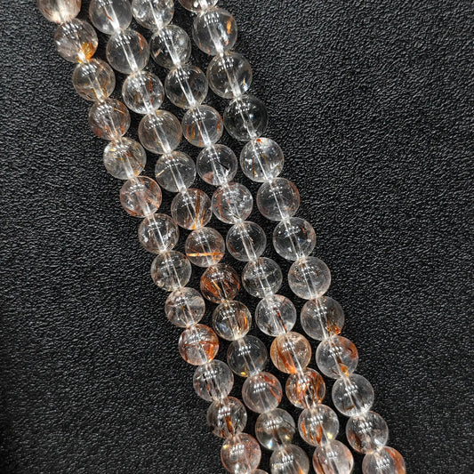 Close up view of statement gemstone beads showing natural copper rutilated quartz strands with clear matrix and reddish copper hair inclusions
