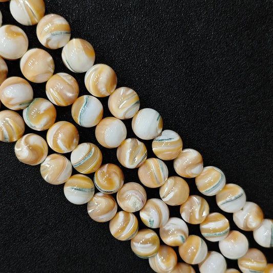 Close up view of statement gemstone beads showing natural spiral shell round strands with distinct cream and apricot organic growth bands