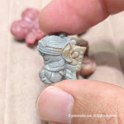 Close up view of a small flower elf figurine in slate green natural stone showing polished wing details