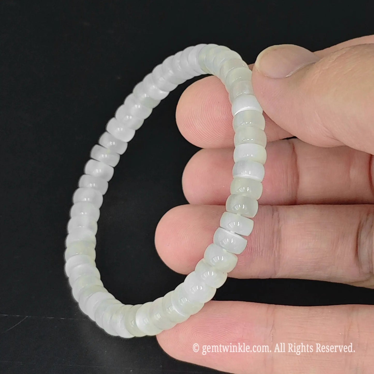 fingers holding translucent 6mm straight cut white moonstone disc bead bracelet