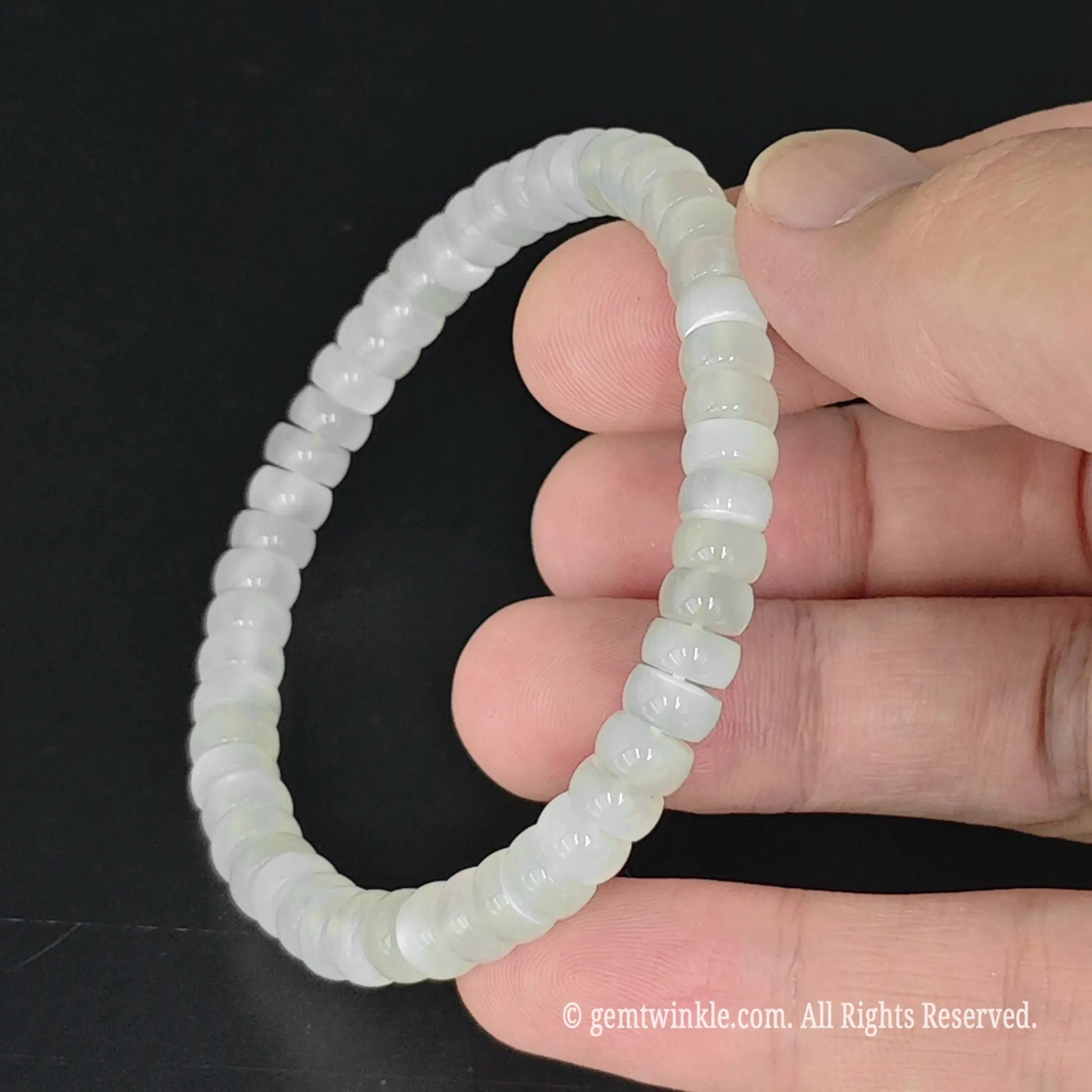 fingers holding translucent 6mm straight cut white moonstone disc bead bracelet