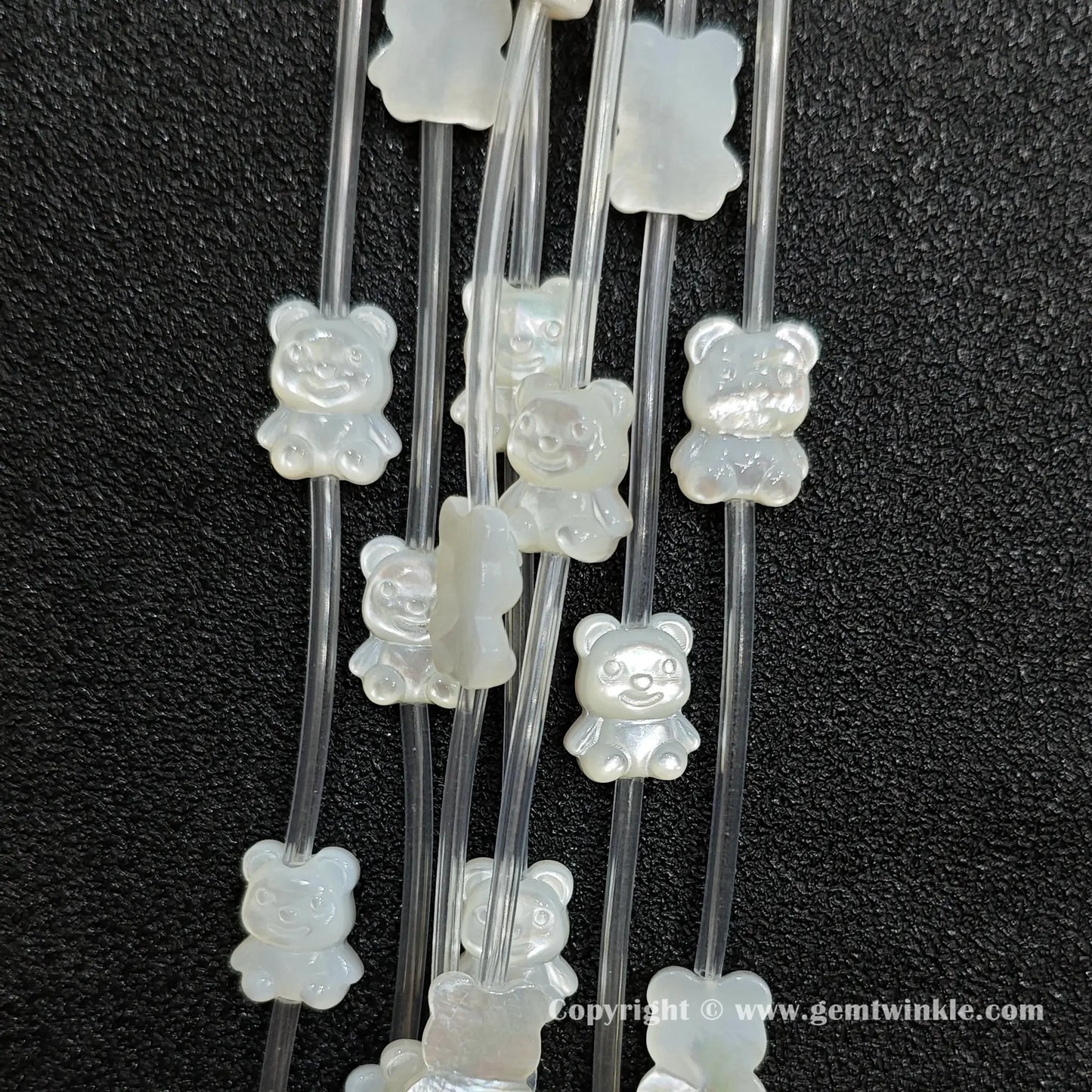 Multiple strands of white mop bear figure beads displaying pearly glow