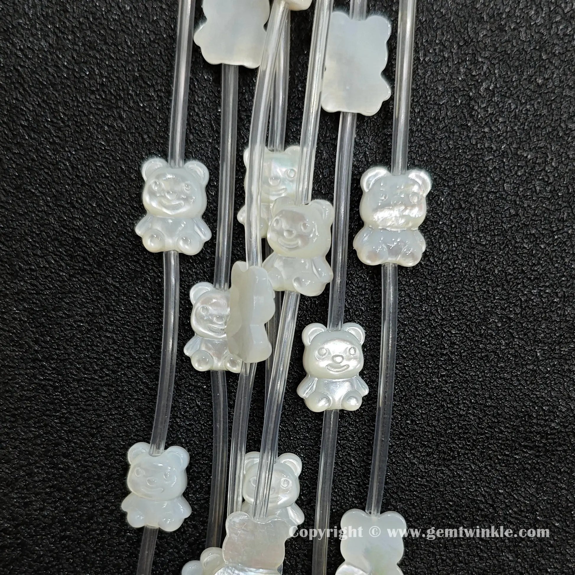 Multiple strands of white mop bear figure beads displaying pearly glow