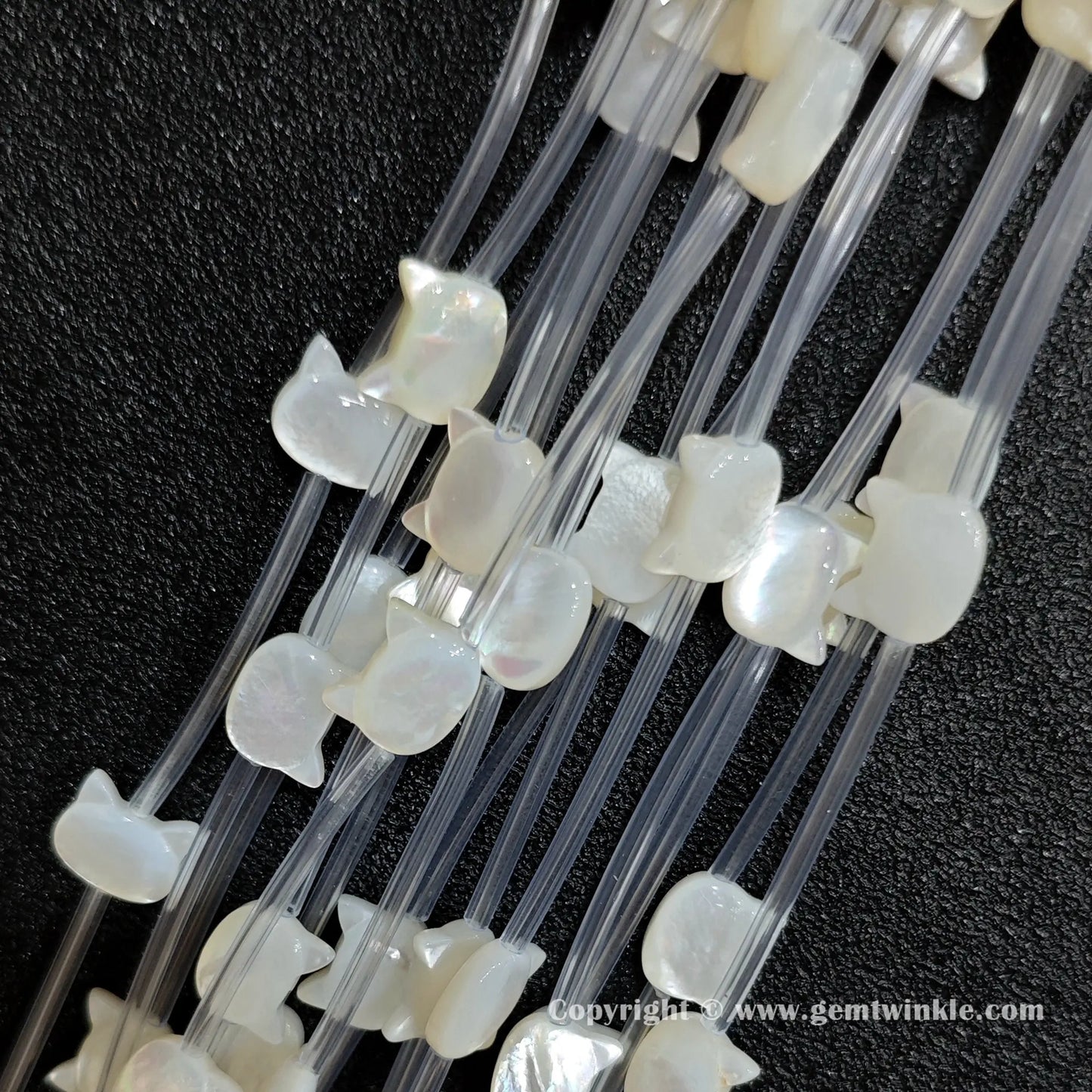 Multiple strands of white mop kitty silhouette beads displaying pearl sheen