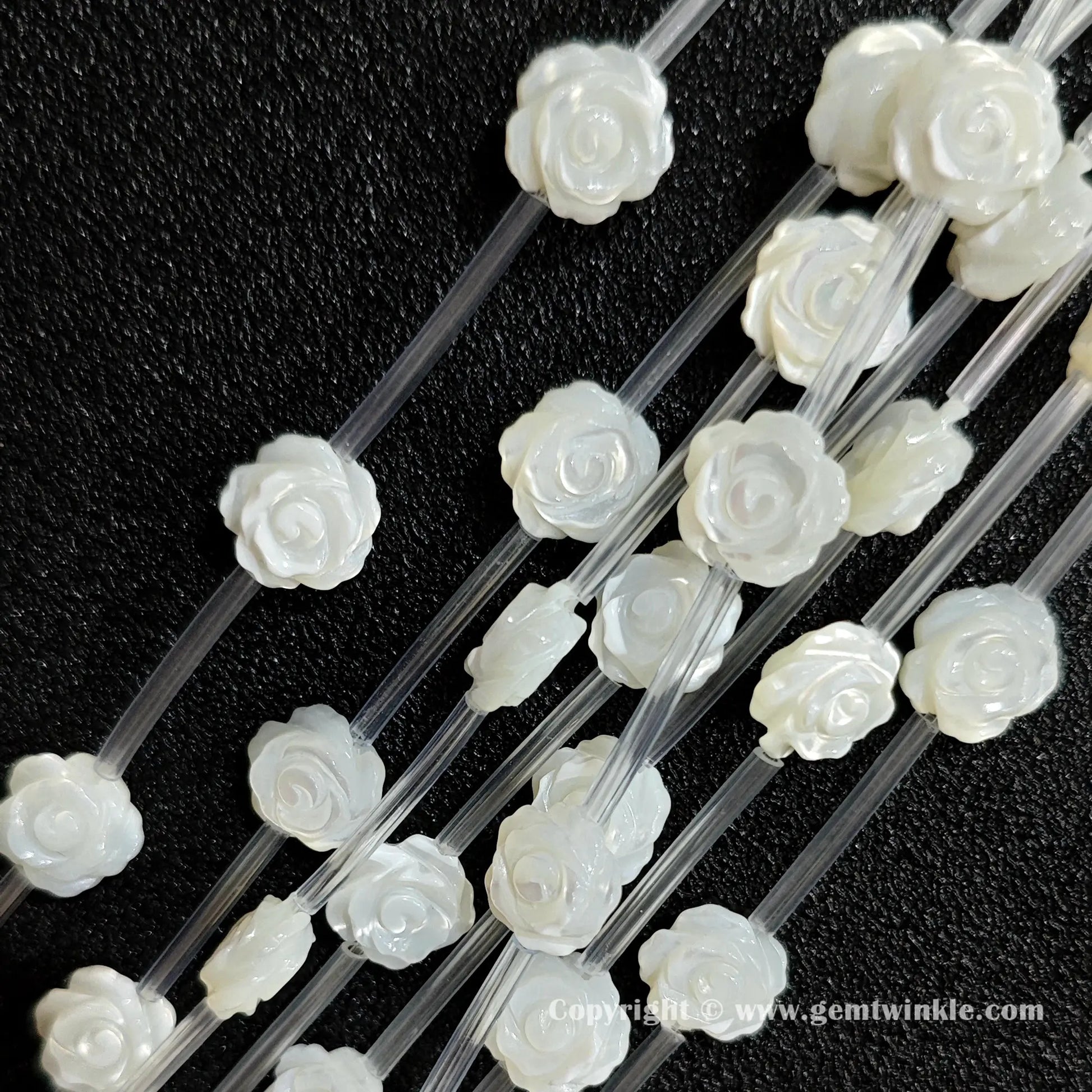 Multiple strands of white mother of pearl rose carving beads displaying pearlescent shine