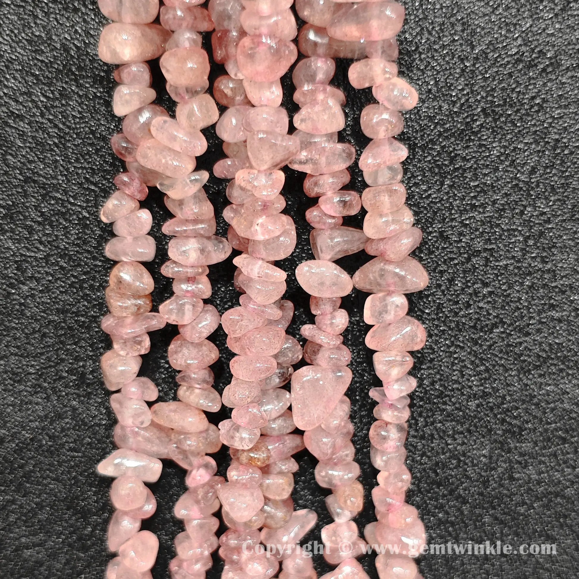 Long strand layout of translucent pink strawberry quartz chip beads for jewelry making