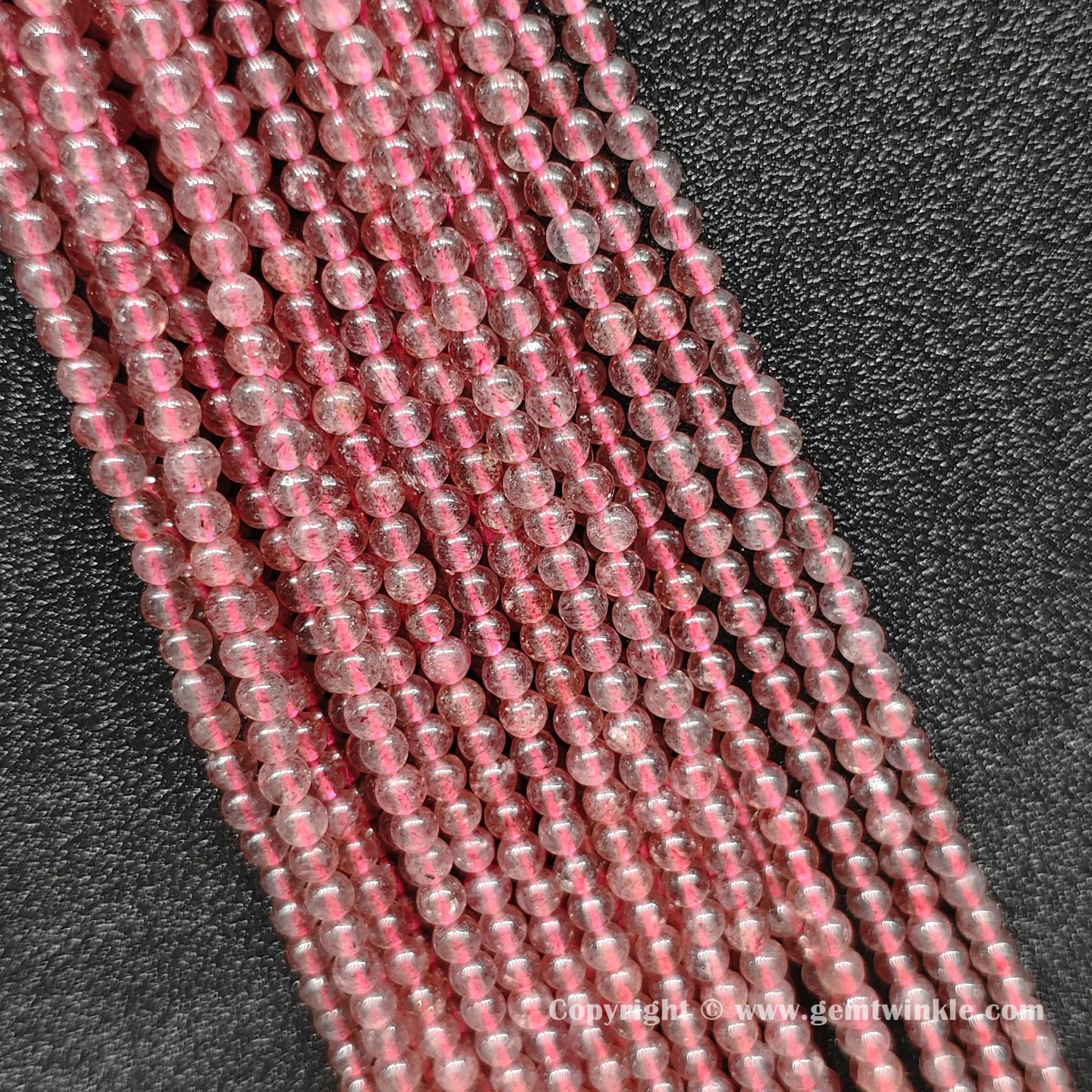 Multiple parallel strawberry quartz round bead strands showing soft pink color