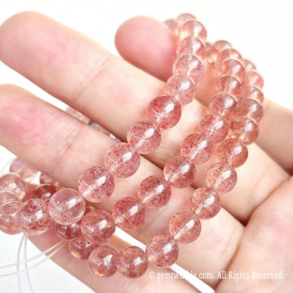 Side angle handheld view of pink strawberry quartzite stretch bracelet showing smooth bead polish and uniform bead sizing