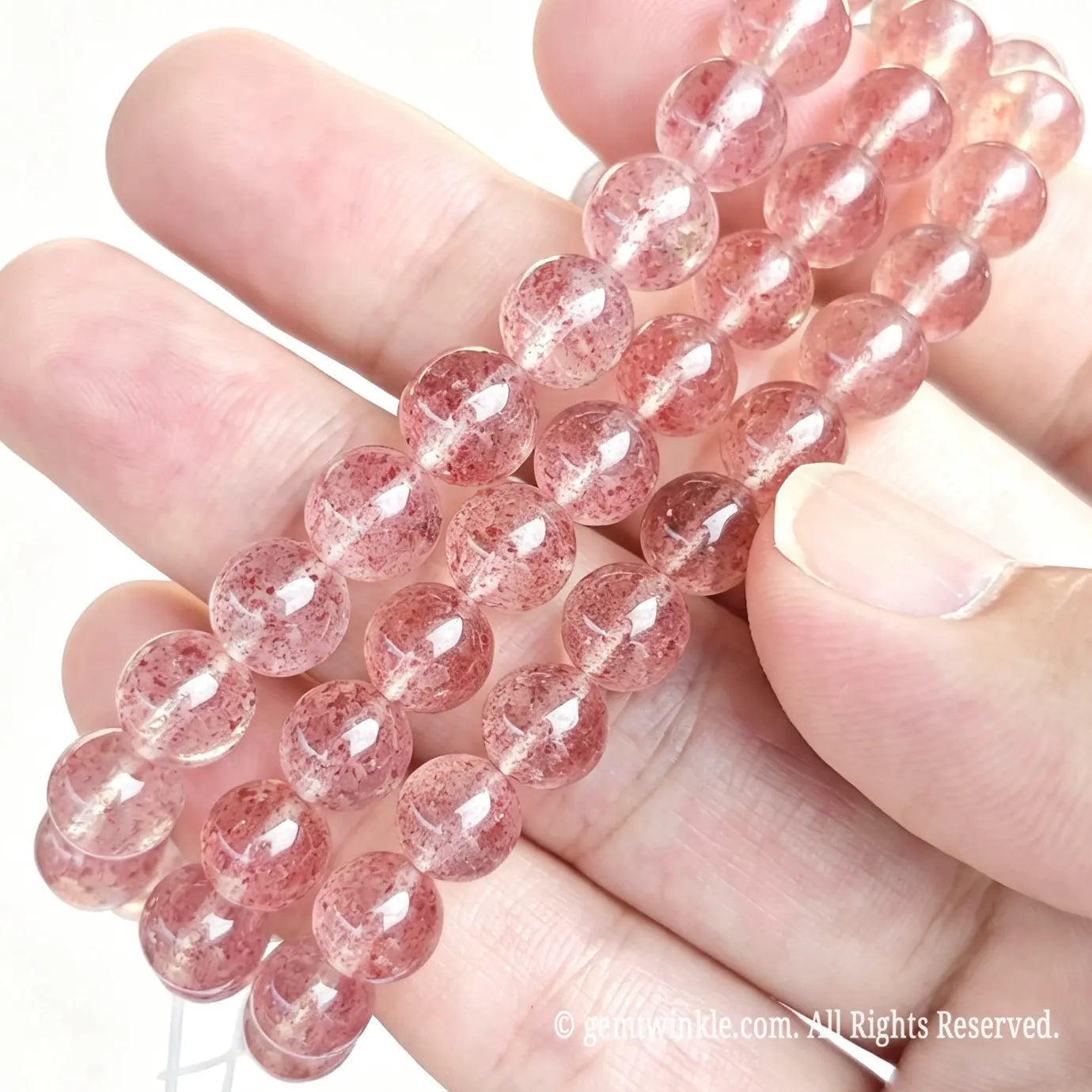 Handheld preview of stacked pink strawberry quartzite stretch bracelets highlighting delicate berry-red speckled inclusions