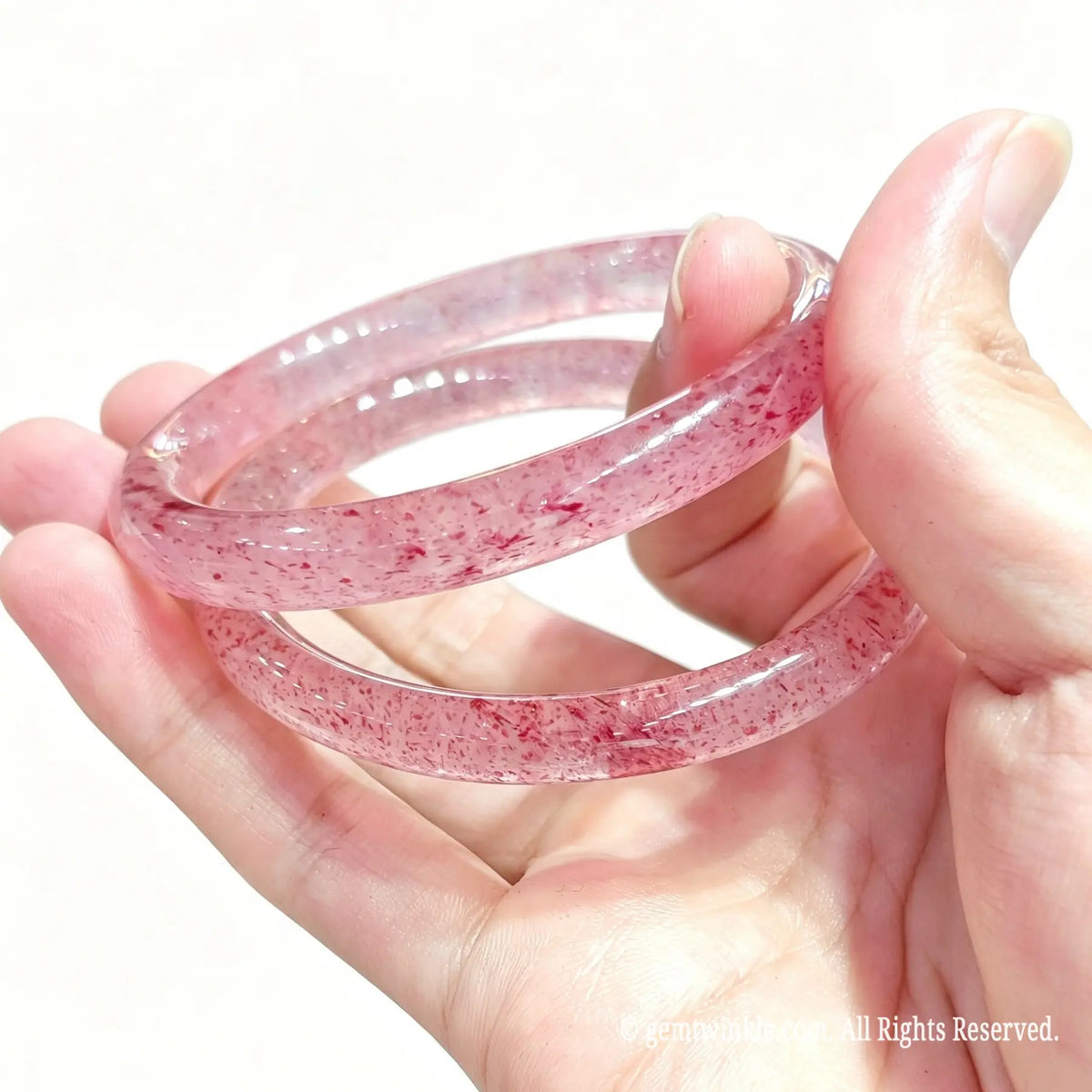 Top view of two natural quartz bangles with scattered red inclusions held together