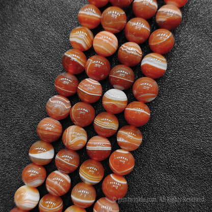 Three strands of vibrant red striped agate loose crystal beads highlighting high polish spherical finish for boutique shop sourcing