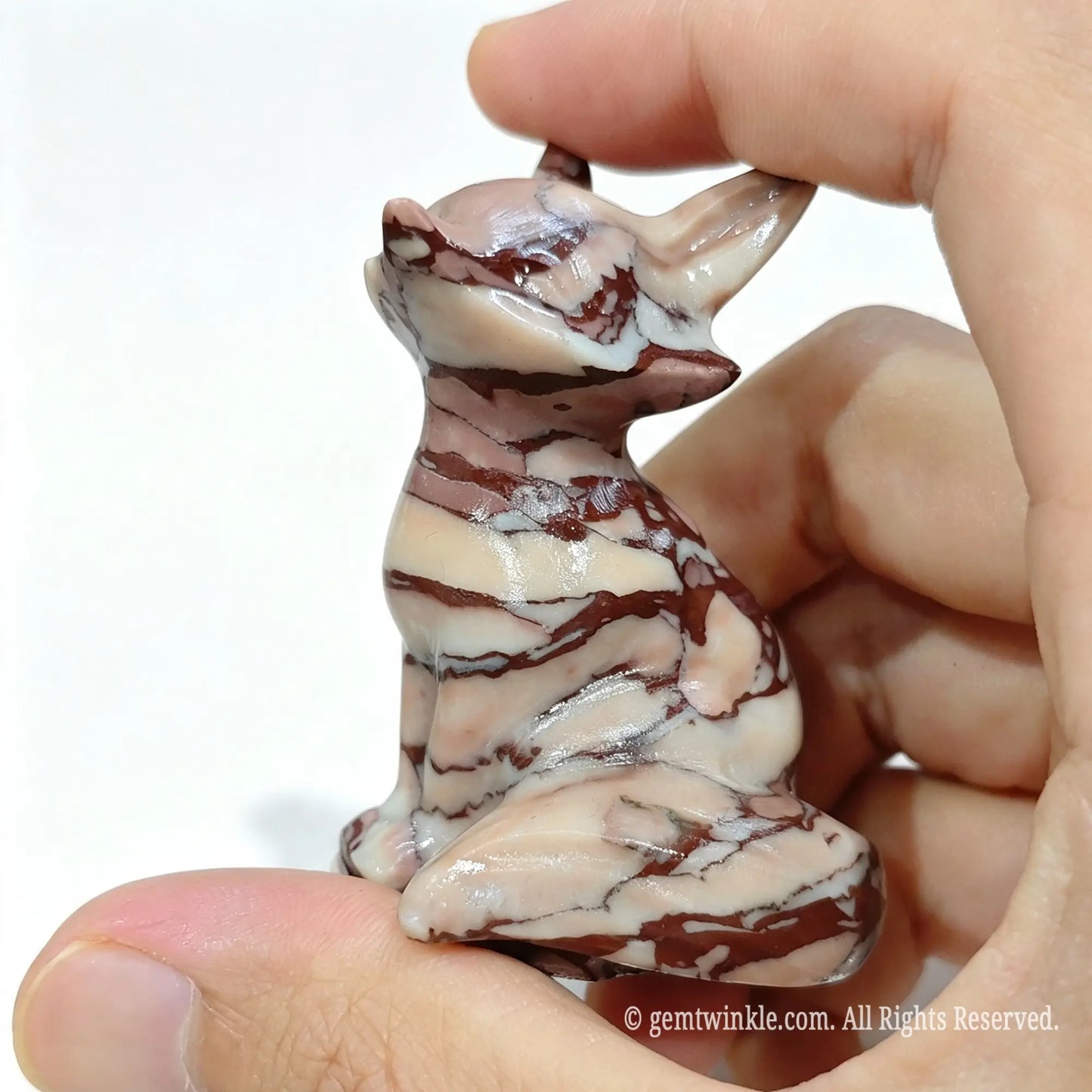 Three-quarter view of striped stone fox sculpture held in hand showcasing smooth polished body contours