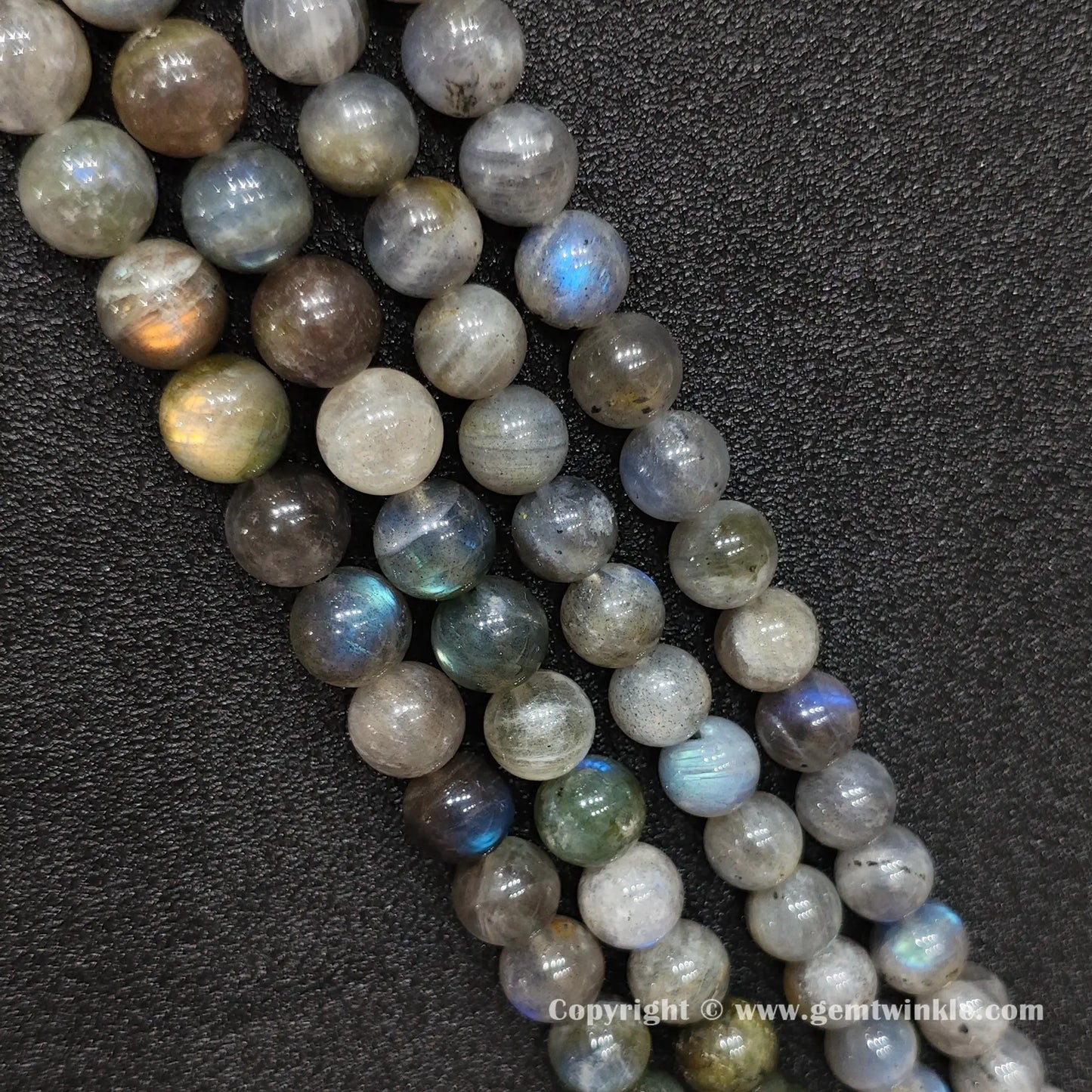 Parallel rows of large natural grey moonstone round strands highlighting glossy polish and earthy grey tones