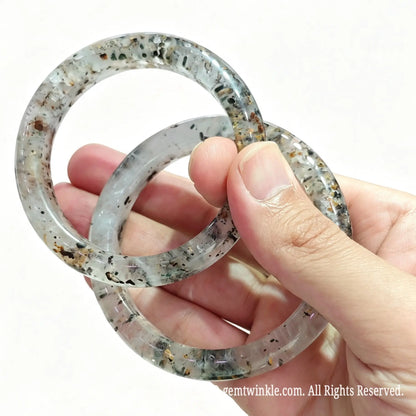 Angled hand view of solid multi mineral quartz bangles showing bright glossy finish and dark tourmaline speckles