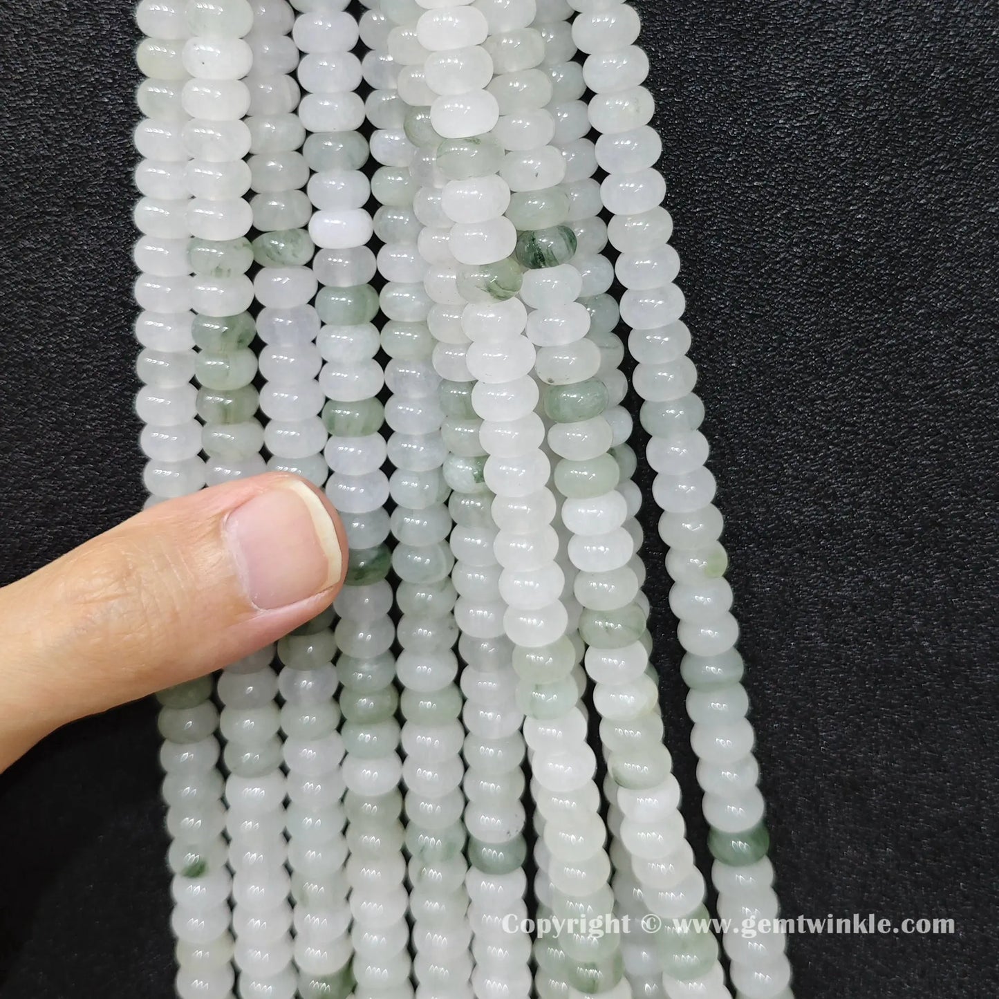 Close up view of 6x4mm tianshan jade smooth disc rondelle beads inspected on fingers for quality preview