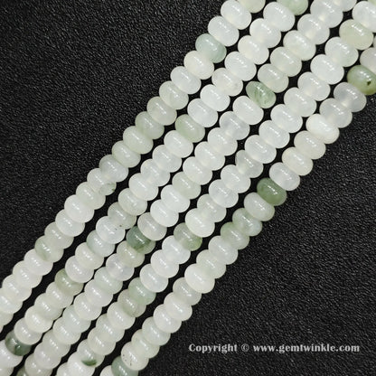 Angled view of natural tianshan jade smooth disc gemstone strands arranged parallel on dark background