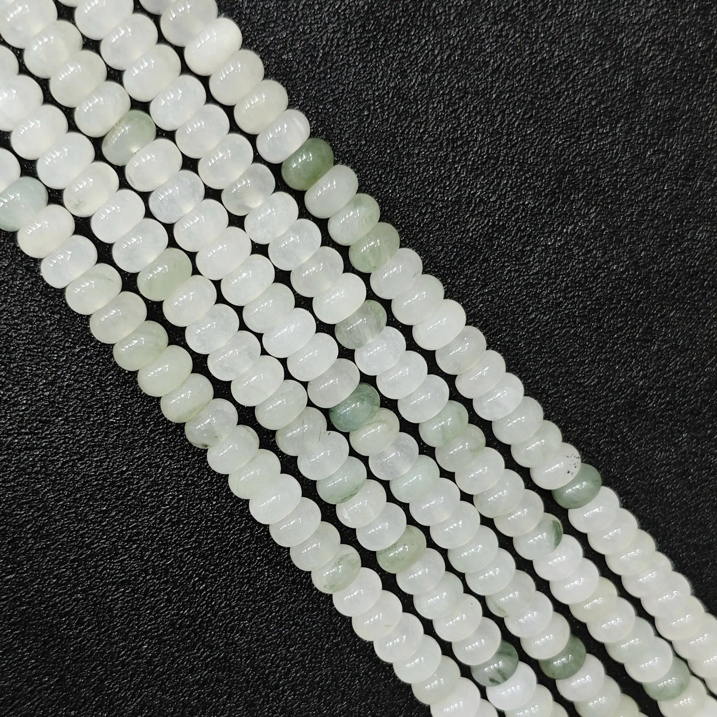 Macro closeup of natural tianshan jade smooth rondelle beads 6x4mm showing icy white and green matrix