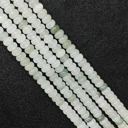 Macro closeup of natural tianshan jade smooth rondelle beads 6x4mm showing icy white and green matrix