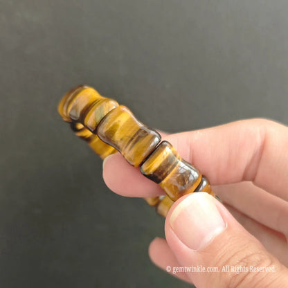 Close-up of carved tiger eye bamboo shaped tube beads showing smooth polished segments and silky light reflection