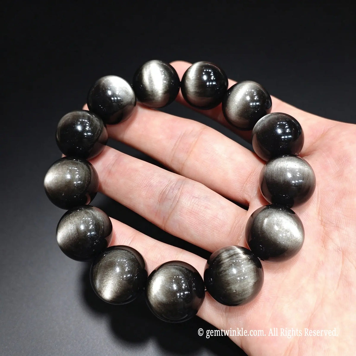 Top grade silver cat eye obsidian stretch bracelet with high polish finish shown against dark background