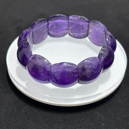 Top view of a natural amethyst rectangle bead bangle bracelet on a white dish, emphasizing the arrangement of the rectangular beads and the overall design.