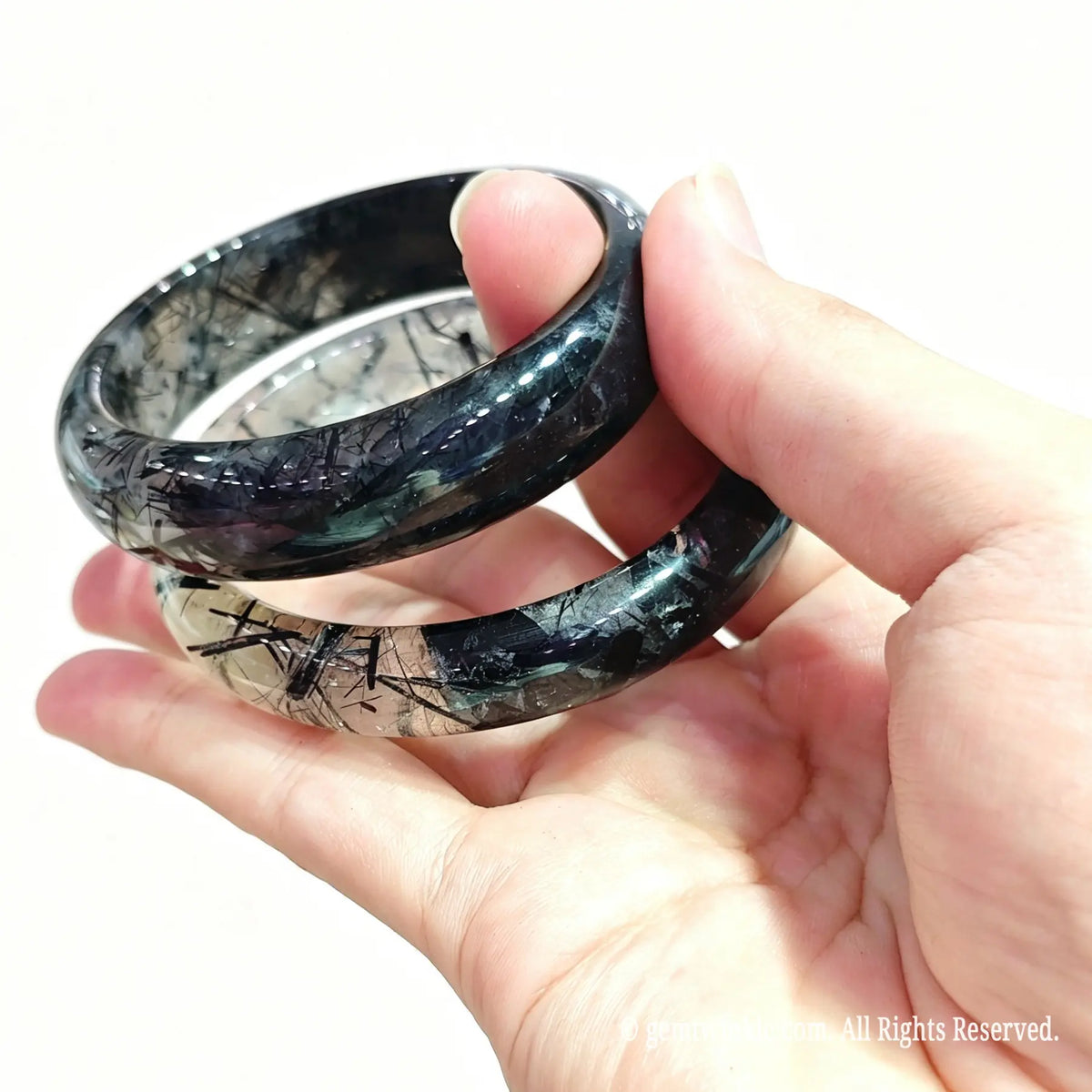 Pair of tourmalinated quartz carved wristbands showing dense silky black needles and high crystal translucency