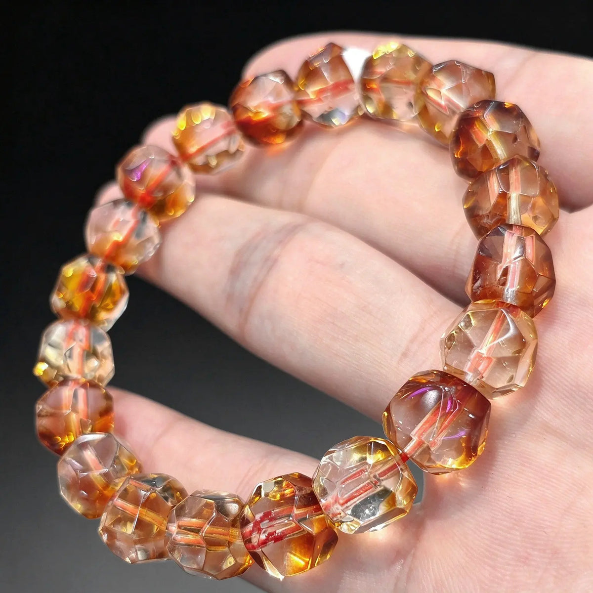 Tower cut citrine quartz bracelet with faceted golden amber beads held on a hand showing light reflection