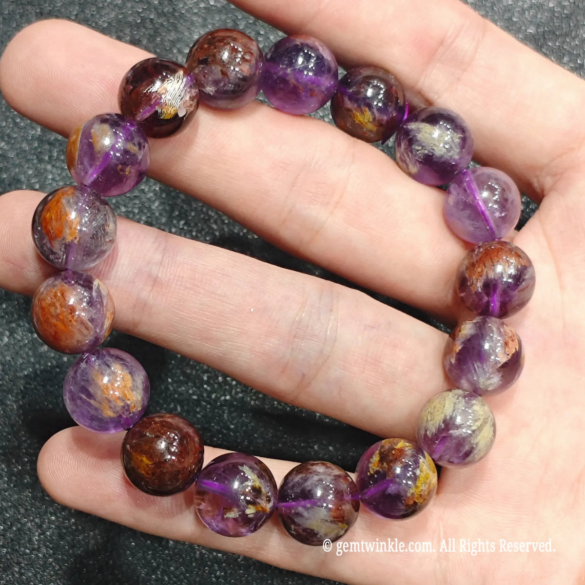 Full view of a translucent amethyst phantom stretch bracelet displayed on hand showing unique rust and purple phantom layers