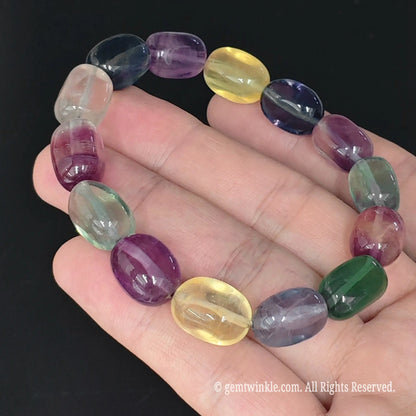 top view of translucent rainbow fluorite candy drum bead bangle held in palm