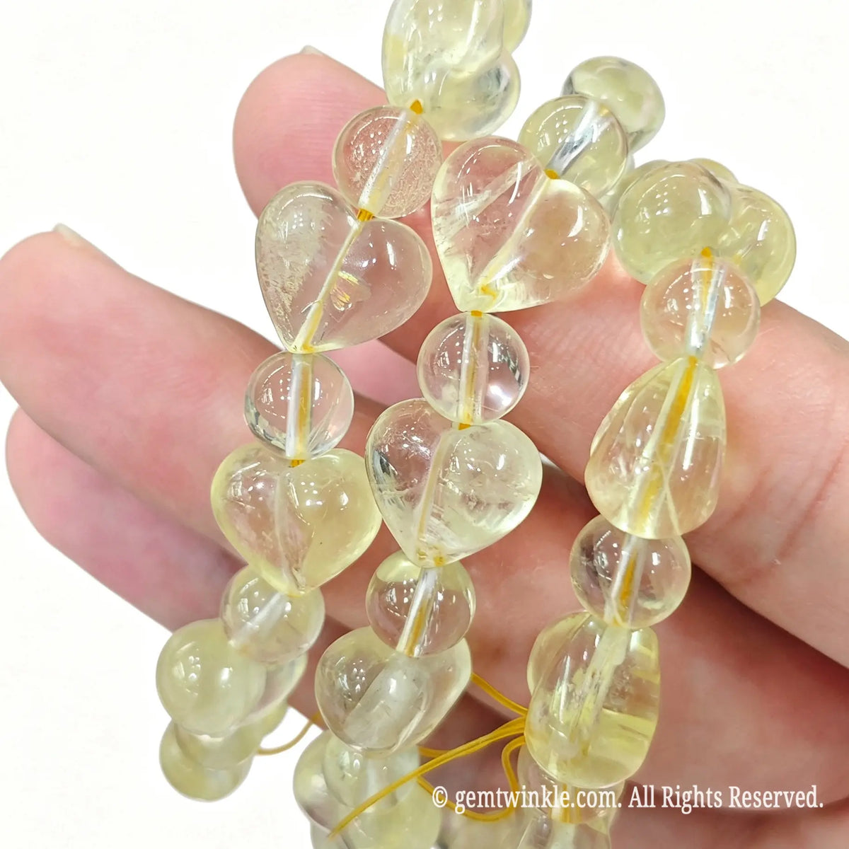 Close up preview of 12mm heart shaped lemon quartz beads highlighting transparency and smooth polish