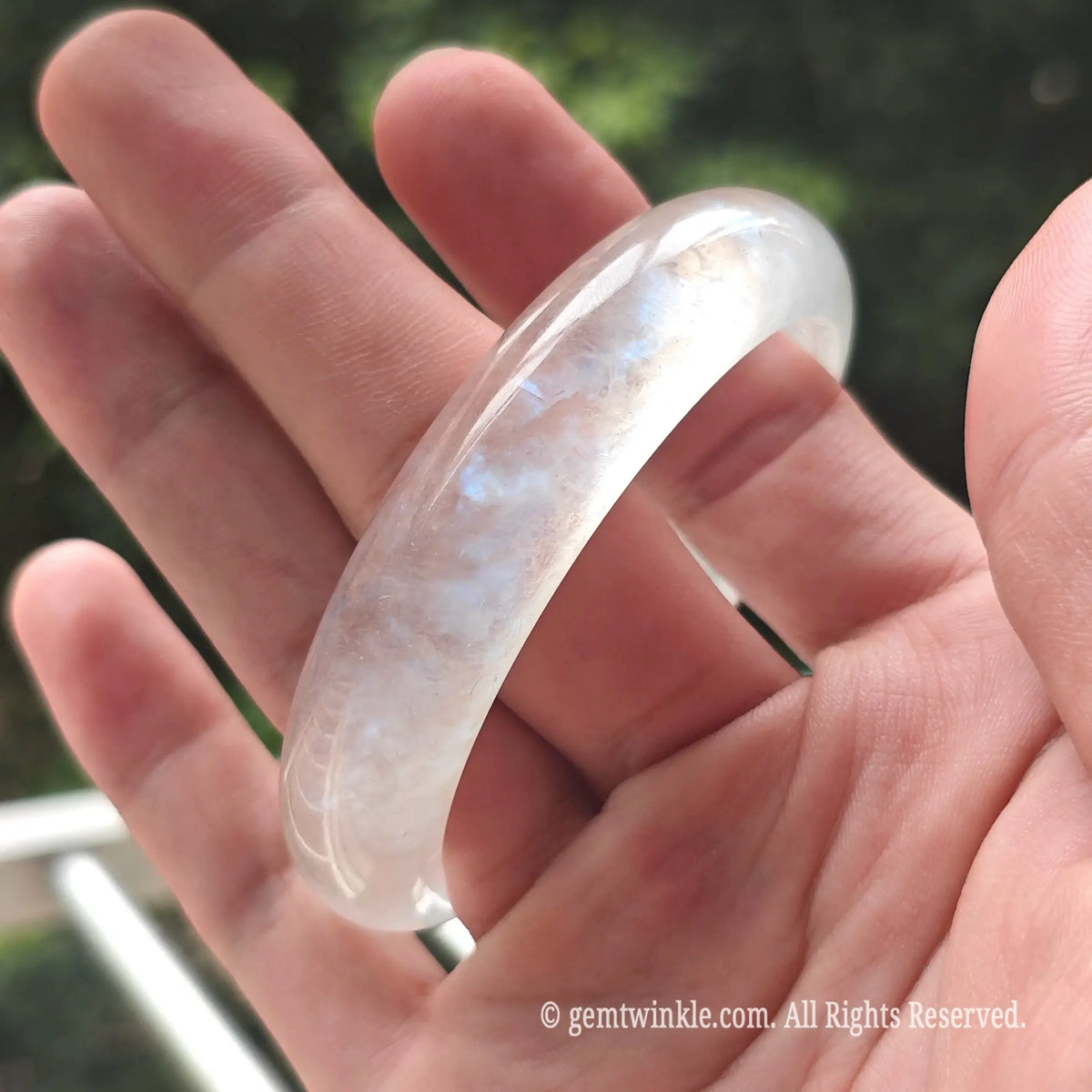 Angled view of an ice-clear blue moonstone gemstone bracelet highlighting its smooth mirror polish