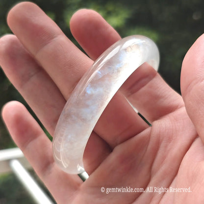 Angled view of an ice-clear blue moonstone gemstone bracelet highlighting its smooth mirror polish