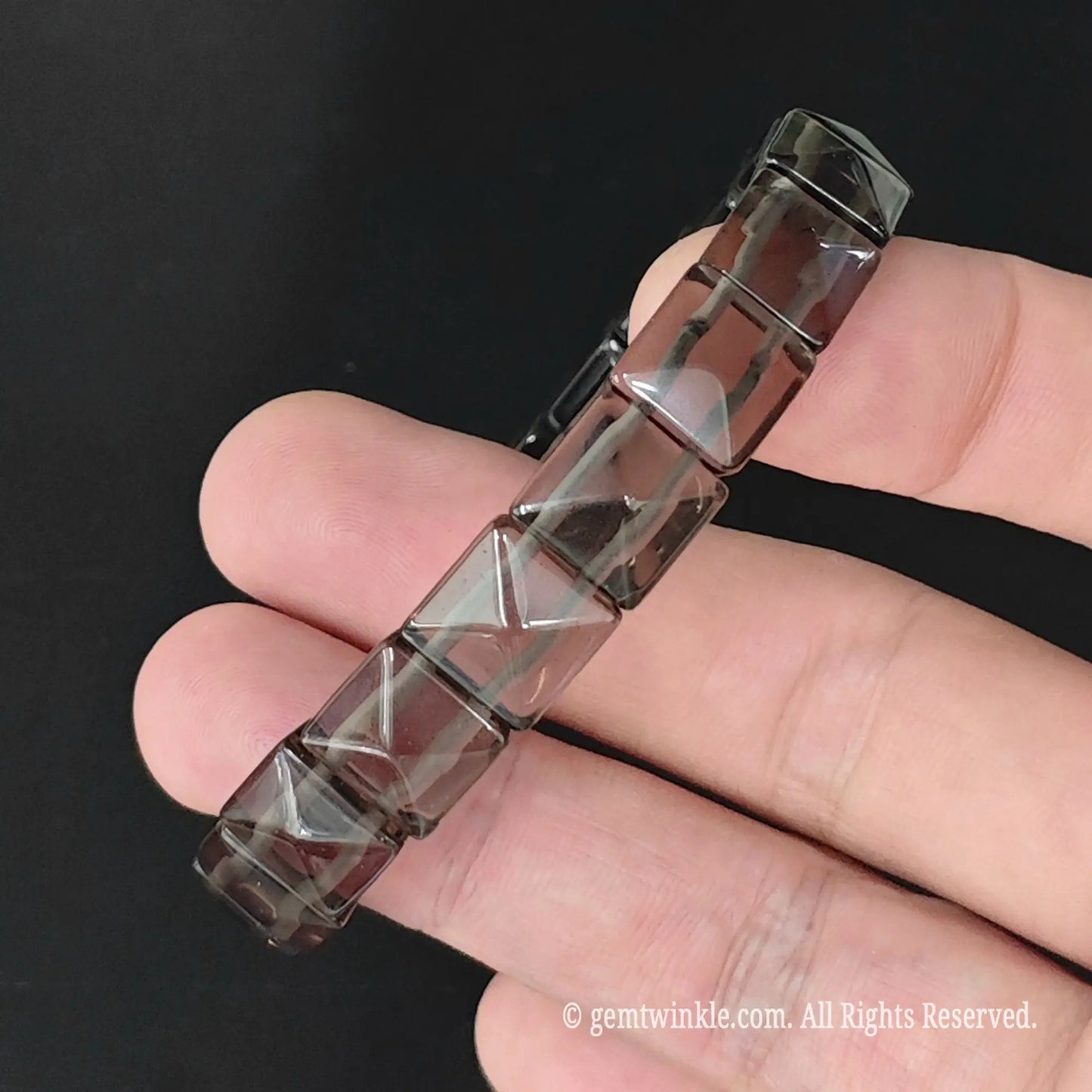 Angle view of translucent ice obsidian faceted pyramid square bead bracelet highlighting light dispersion across facets